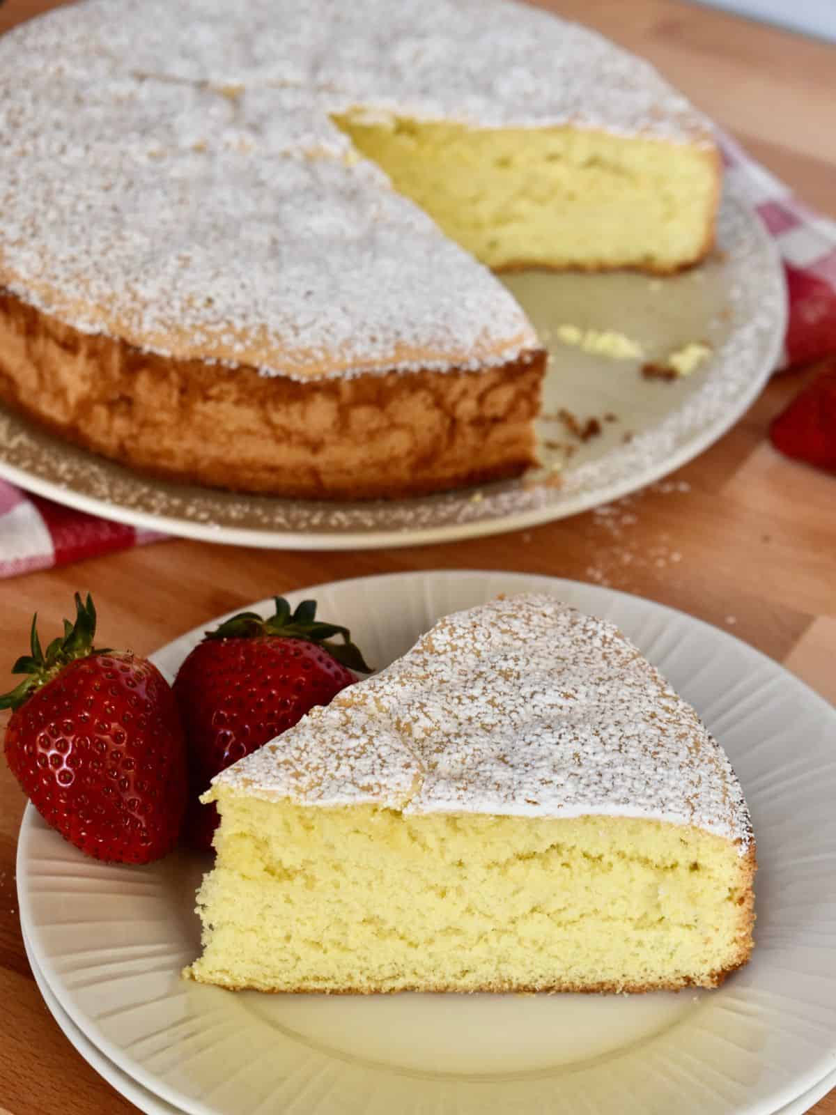 slice of Italian torta Margherita in a white plate with strawberries. 