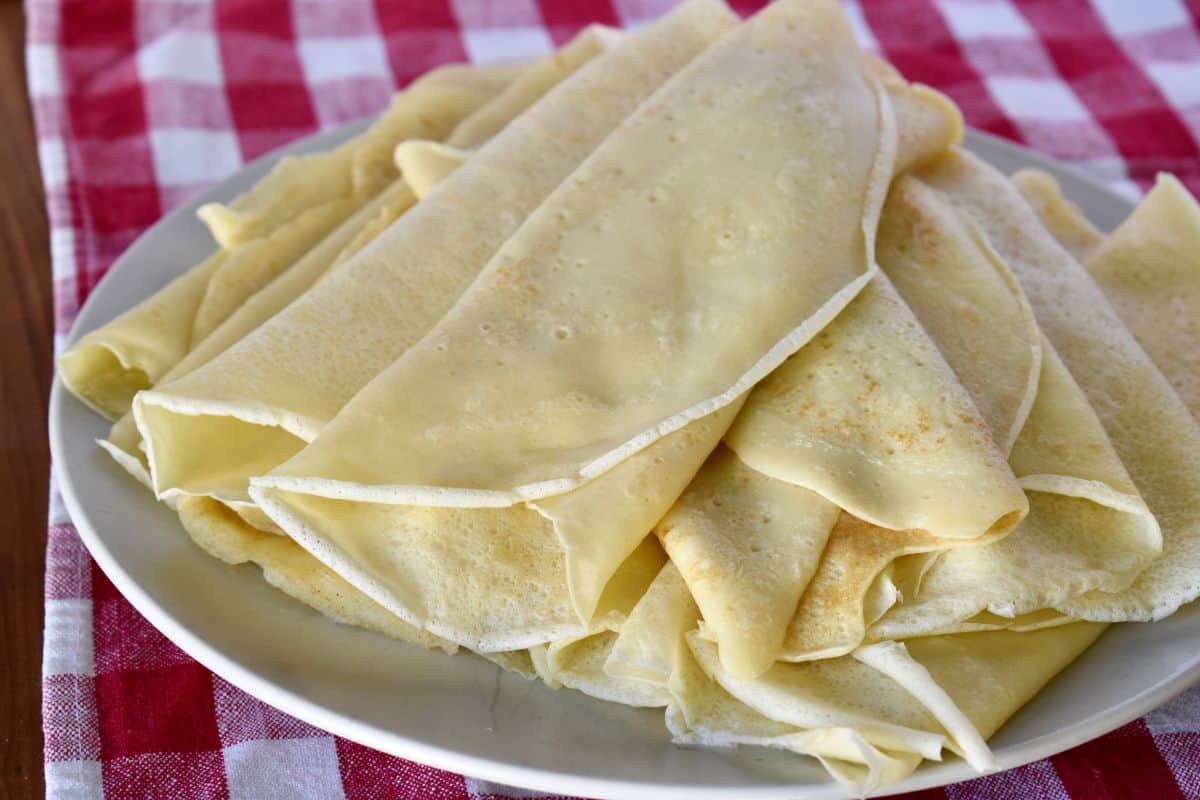 Crespelle on a plate with a checkered napkin underneath. 