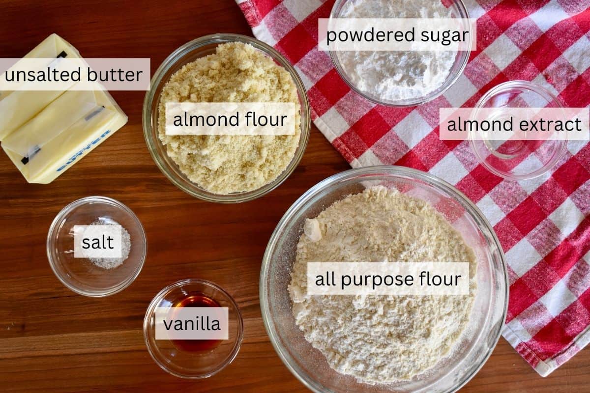 Overhead photo of ingredients including flour, almond flour, butter, almond extract, and powdered sugar. 