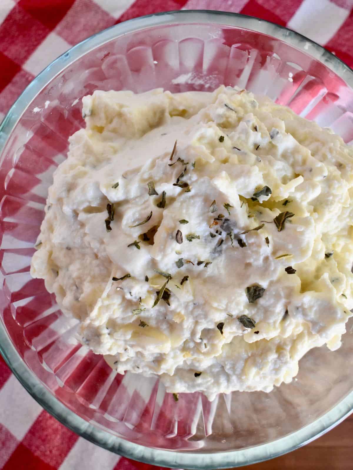 Overhead photo of ricotta filling recipe in a glass bowl on a checkered napkin.