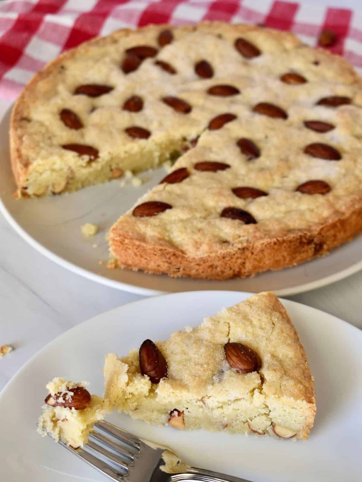 Sbrisolona Torta on a white plate with a checkered napkin in the background. 