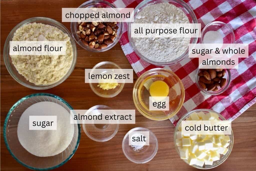 Ingredients on a countertop including almonds, almond flour, sugar, and an egg. 