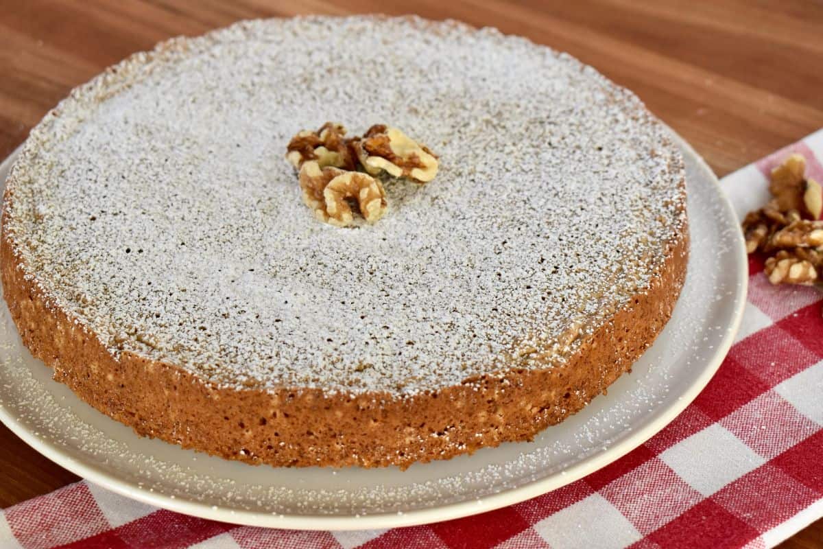 Torta di Noci on a white plate with powdered sugar sprinkled on top. 