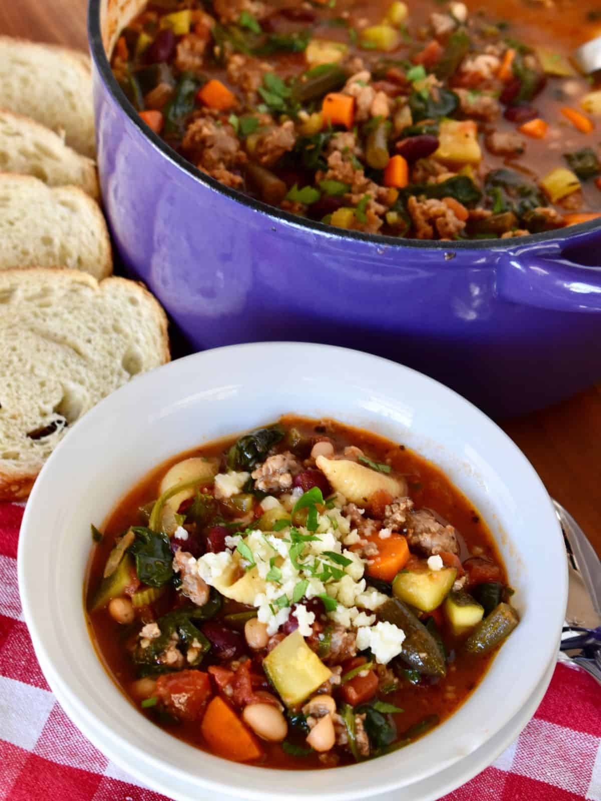 Minestrone soup with sausage in a pot with bread. 
