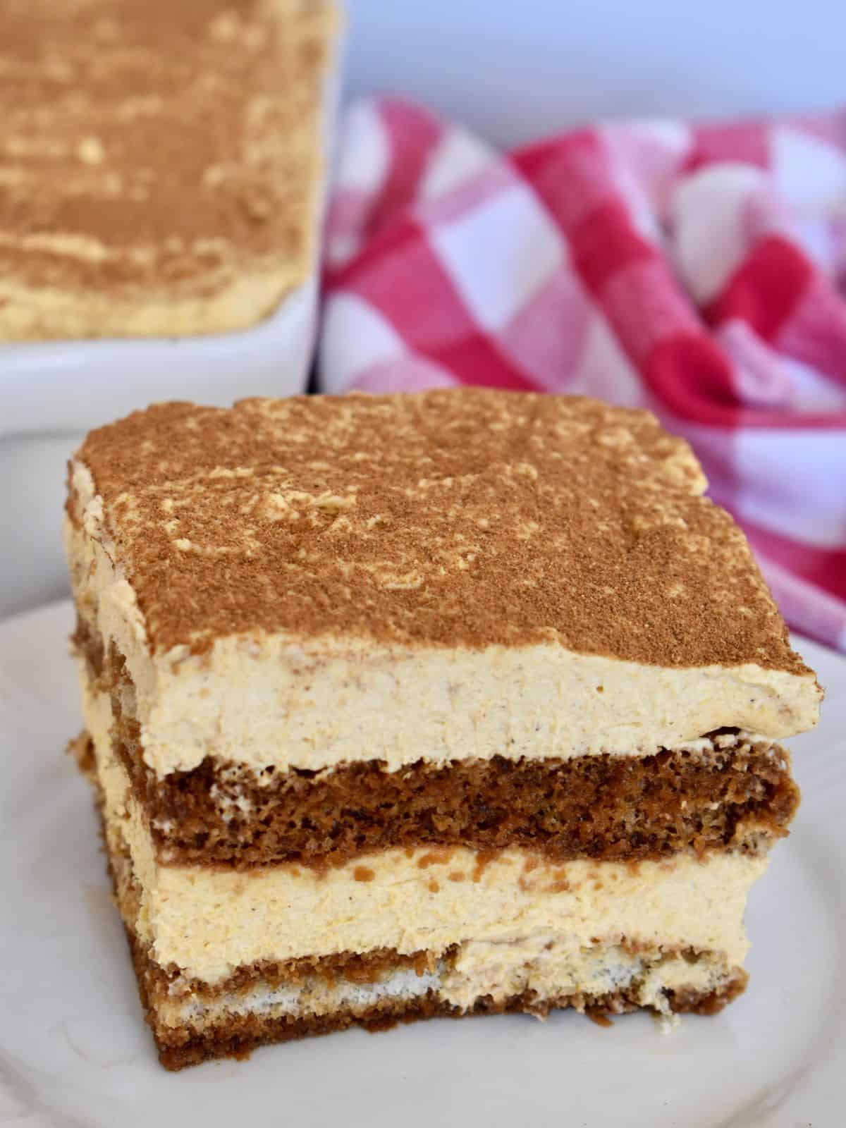 Pumpkin tiramisu on a white plate with a checkered napkin in the background. 
