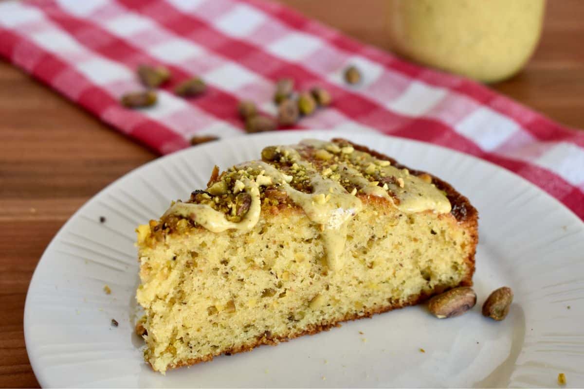 Slice of Italian Pistachio Cake on a white plate with a drizzle of pistachio cream on top. 