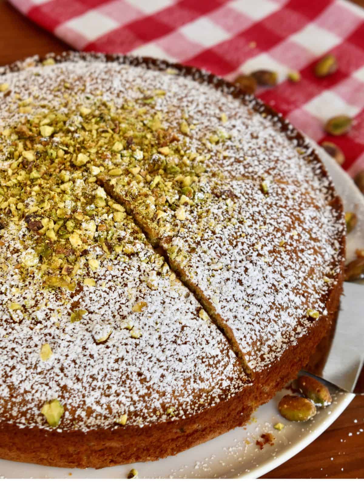 Italian Pistachio Cake on a plate with a checkered napkin in the background.
