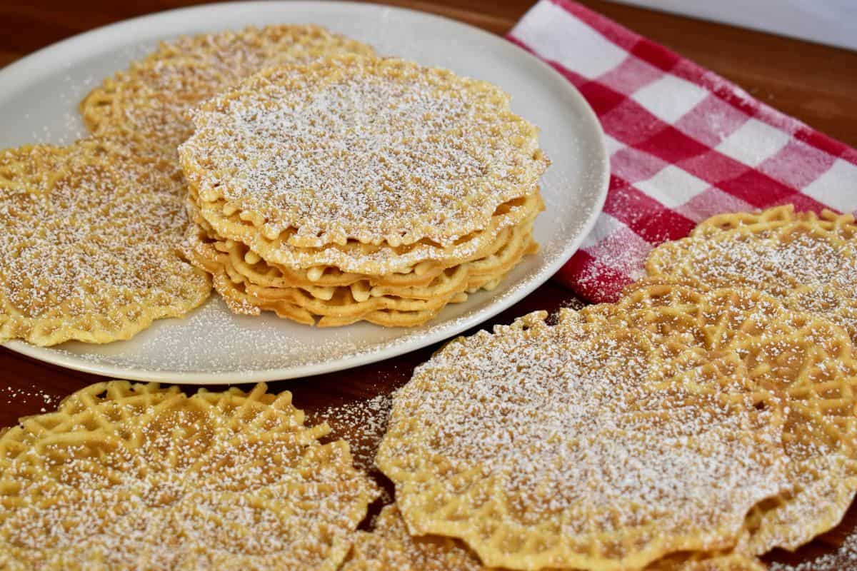 Italian Pizzelle cookies stacked on each other with powdered sugar sprinkled on top. 