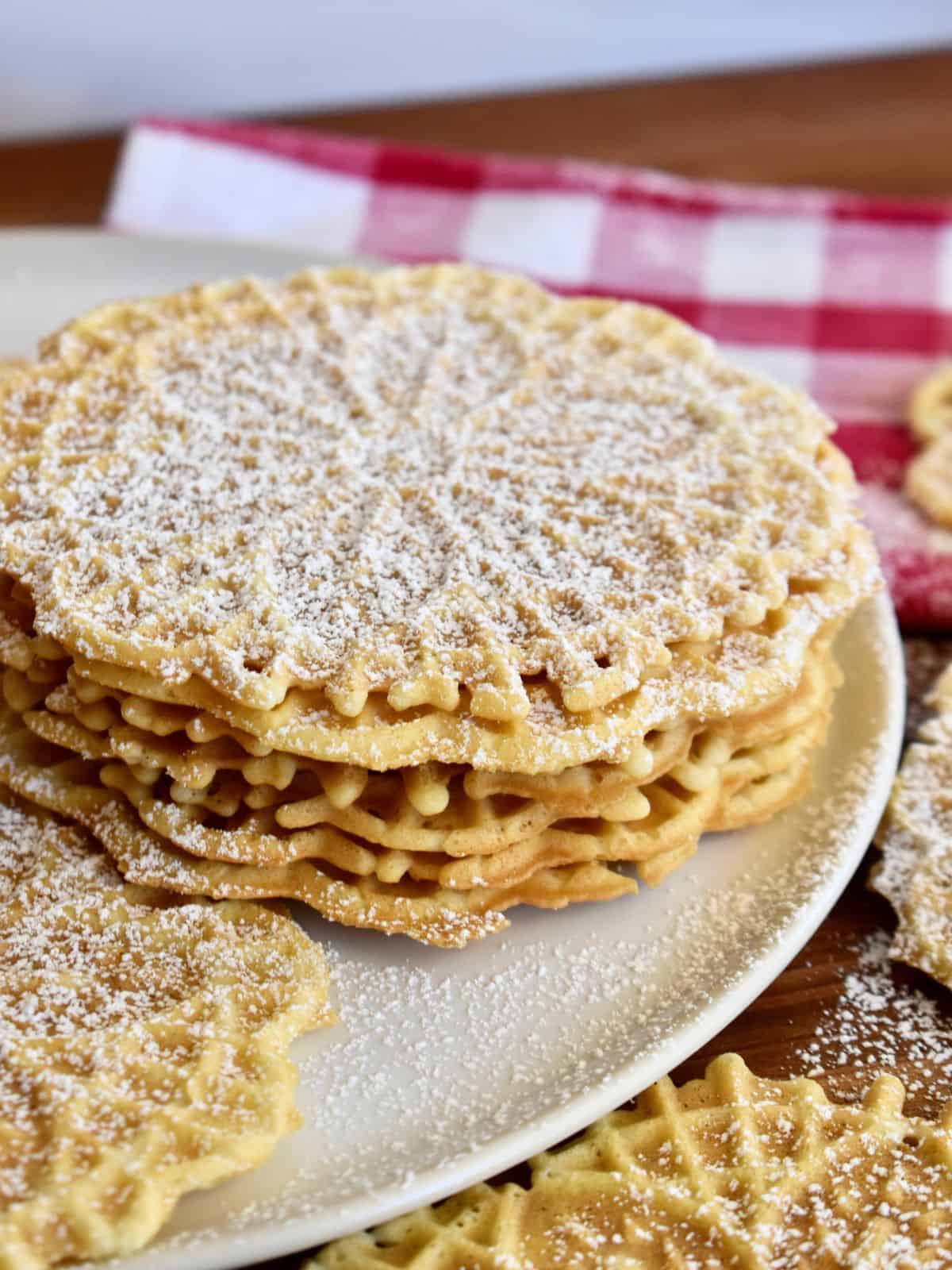 Pizzelle stacked on each other on a white plate. 