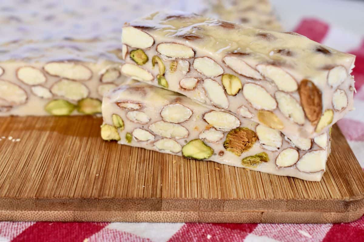 Slices of Torrone candy on a wood cutting board. 