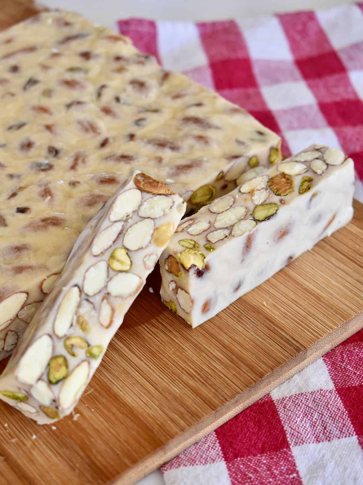 Torrone sliced on a countertop with a checkered napkin in the background. 