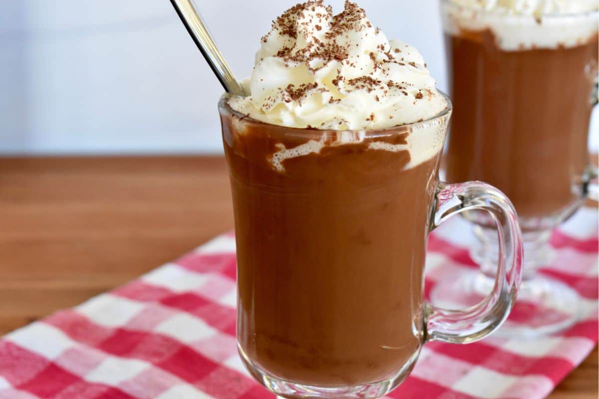 Cioccolata Calda in a glass mug with whipped cream on top. 