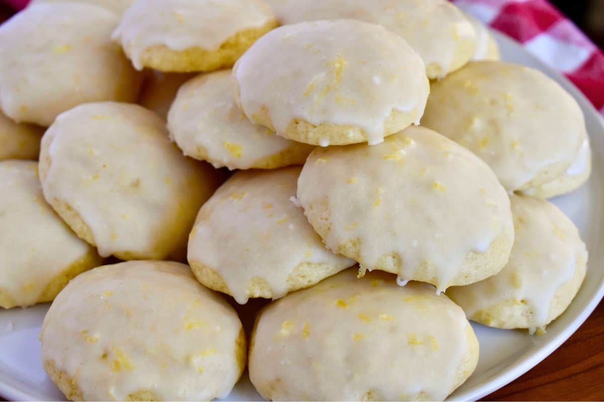 Glazed Italian Lemon Drop Cookies stacked on a white plate. 