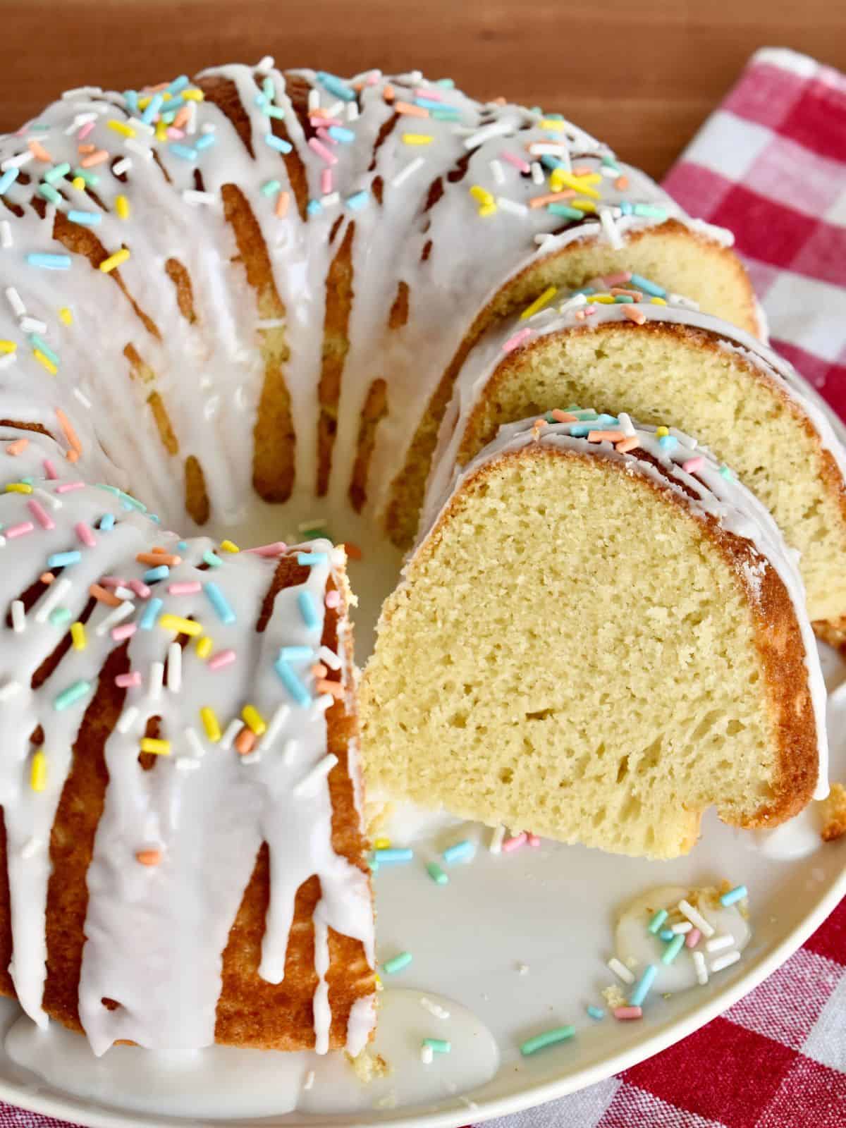 Italian Easter Cake on a white plate with frosting and sprinkles on top.