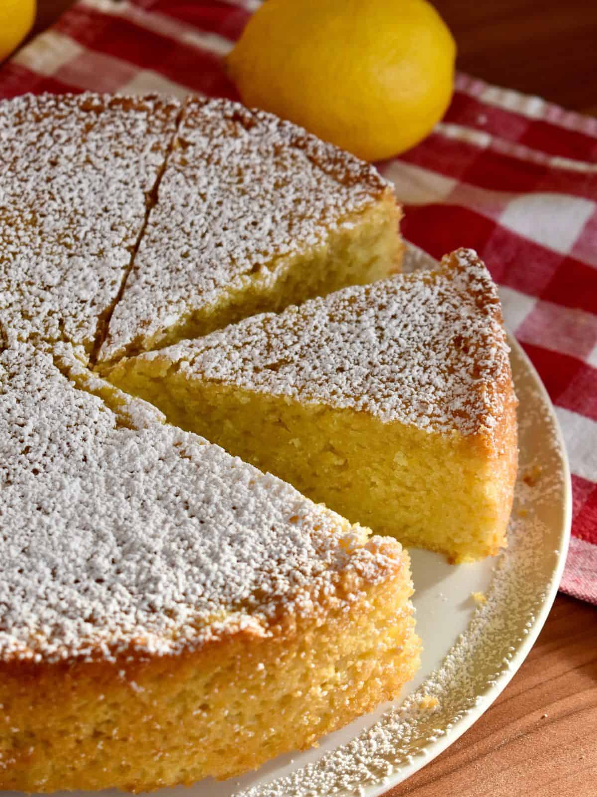 Italian Lemon Olive Oil Cake on a white plate with a checkered napkin in the background. 