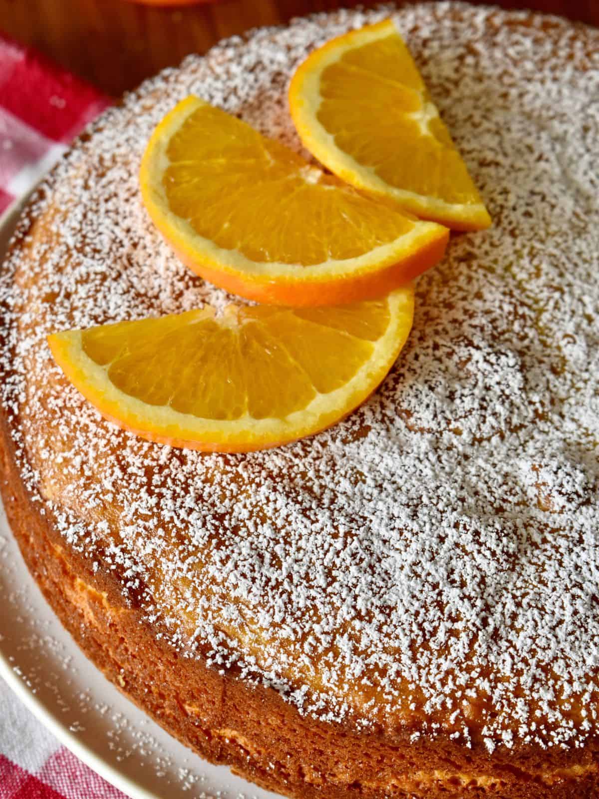 Italian whole orange cake topped with powdered sugar and sliced oranges. 