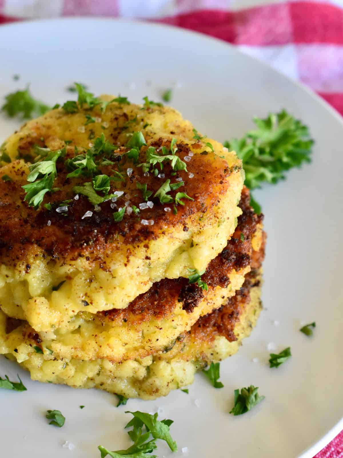 Risotto Cakes on a white plate with parsley on top. 
