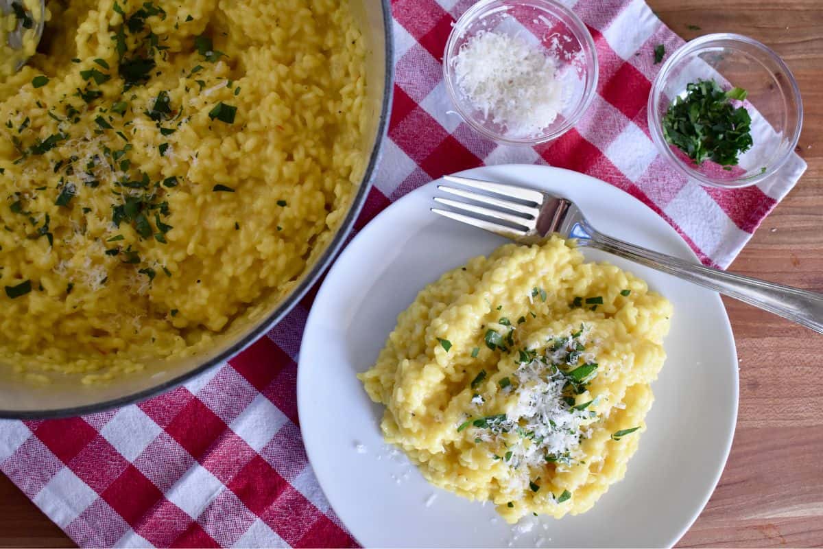 Risotto Milanese on a white plate with a checkered napkin underneath. 