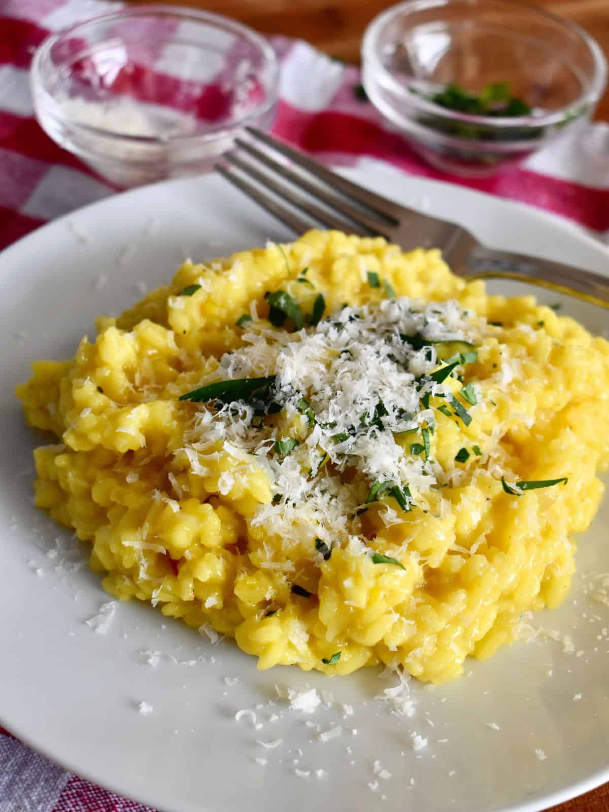 Risotto alla Milanese on a white plate with a fork. 