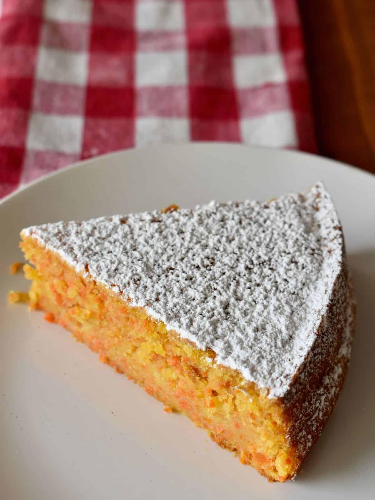 Slice of Italian Carrot Cake on a white plate with powdered sugar on top. 