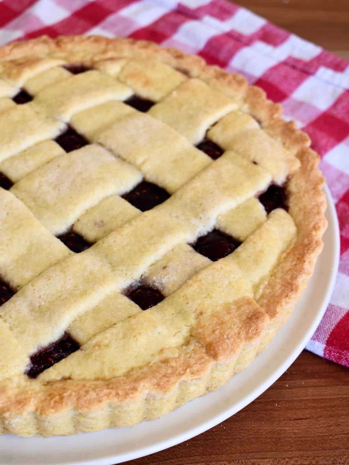 Italian Crostata with a lattice top on a white serving platter. 