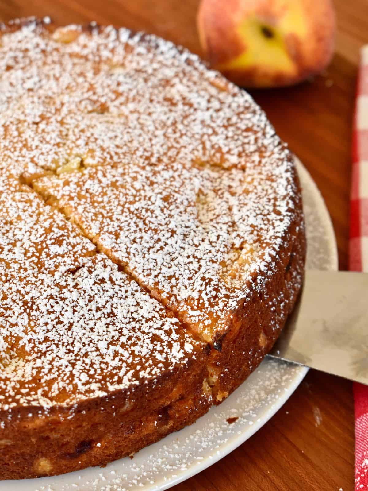 Peach ricotta cake with powdered sugar sprinkled on top and cut into pieces. 