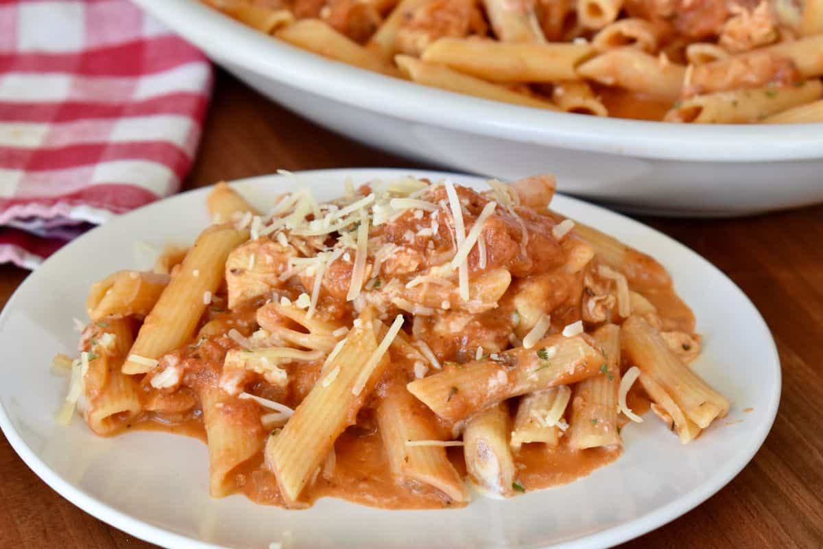 Penne alla vodka with chicken in a serving bowl with parmesan cheese sprinkled on top. 