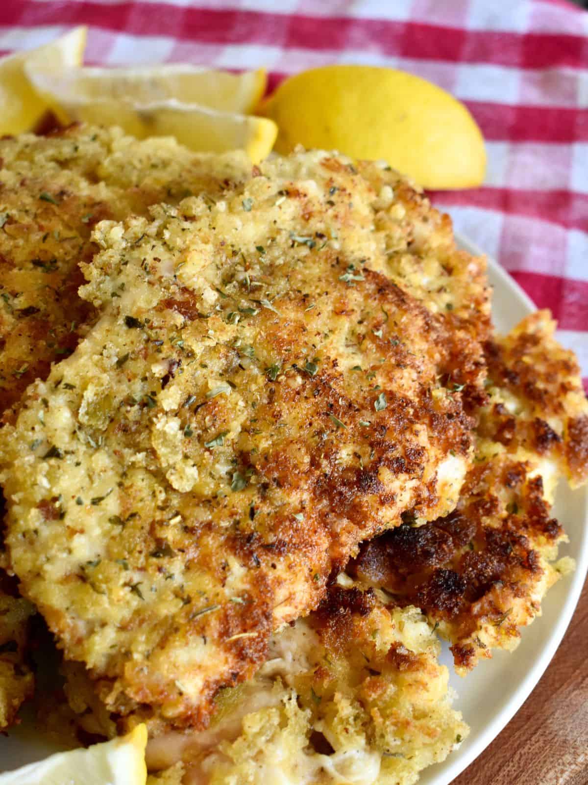 Italian Chicken Cutlets on a white plate with slices of lemon. 