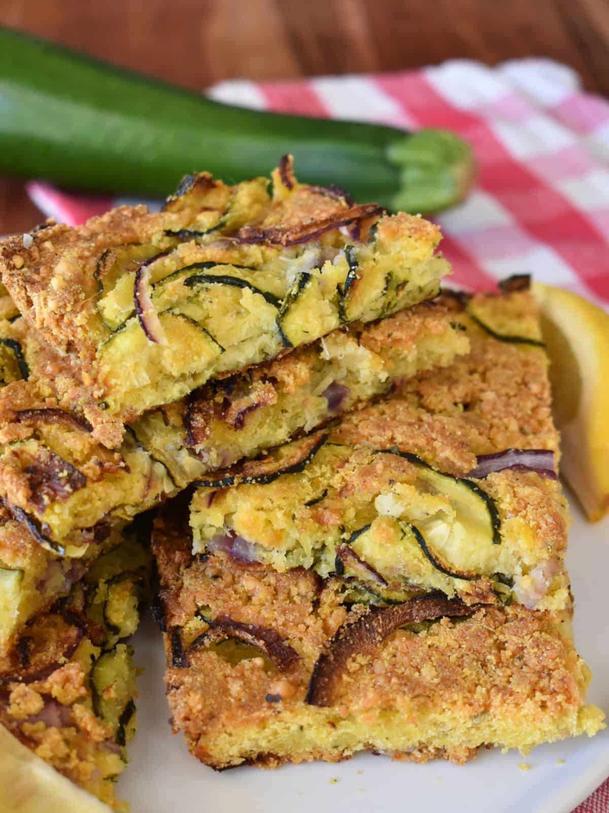 Italian Zucchini Scarpaccia on a white plate with a zucchini in the background. 