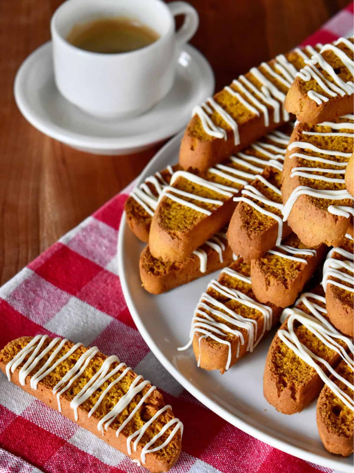 Pumpkin Biscotti on a white plate with a cup of coffee nearby. 