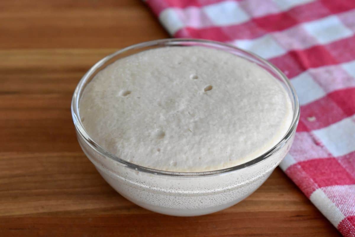 Glass bowl with proofed foamy yeast. 