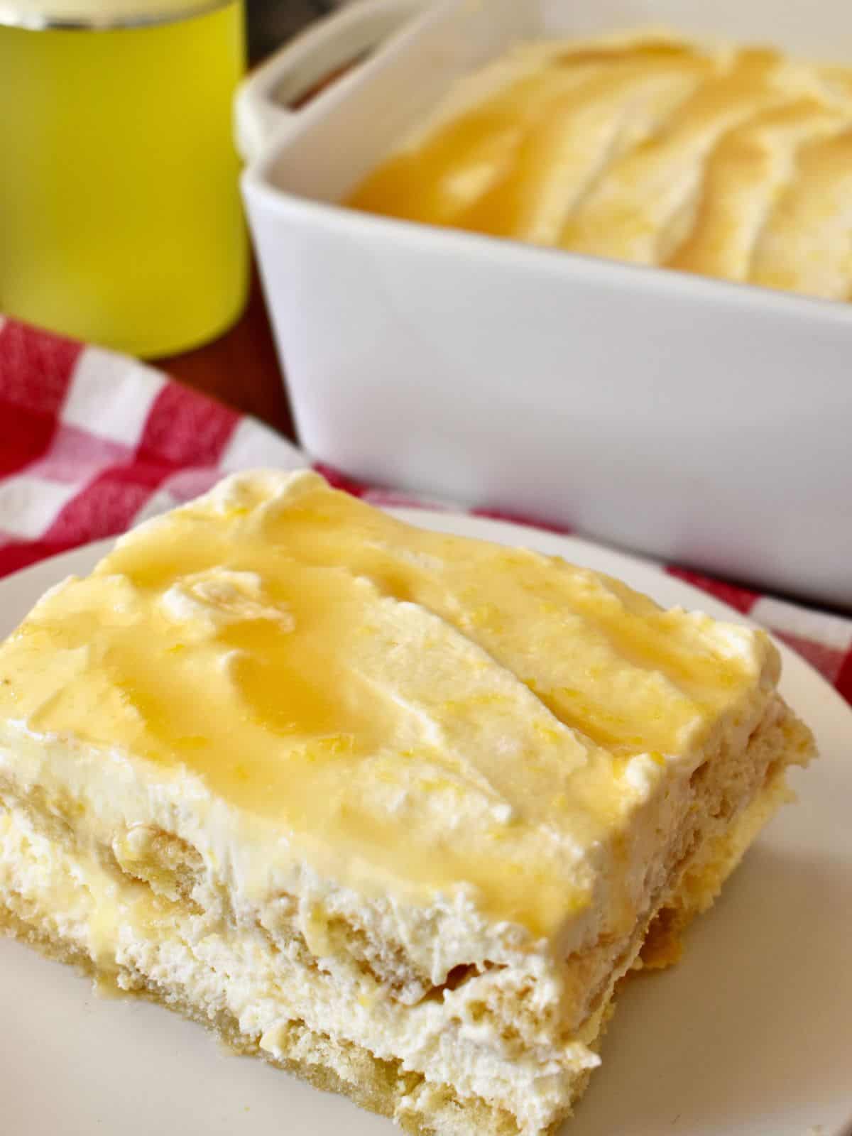 Limoncello Tiramisu on a white plate with a bottle of limoncello liqueur behind it. 