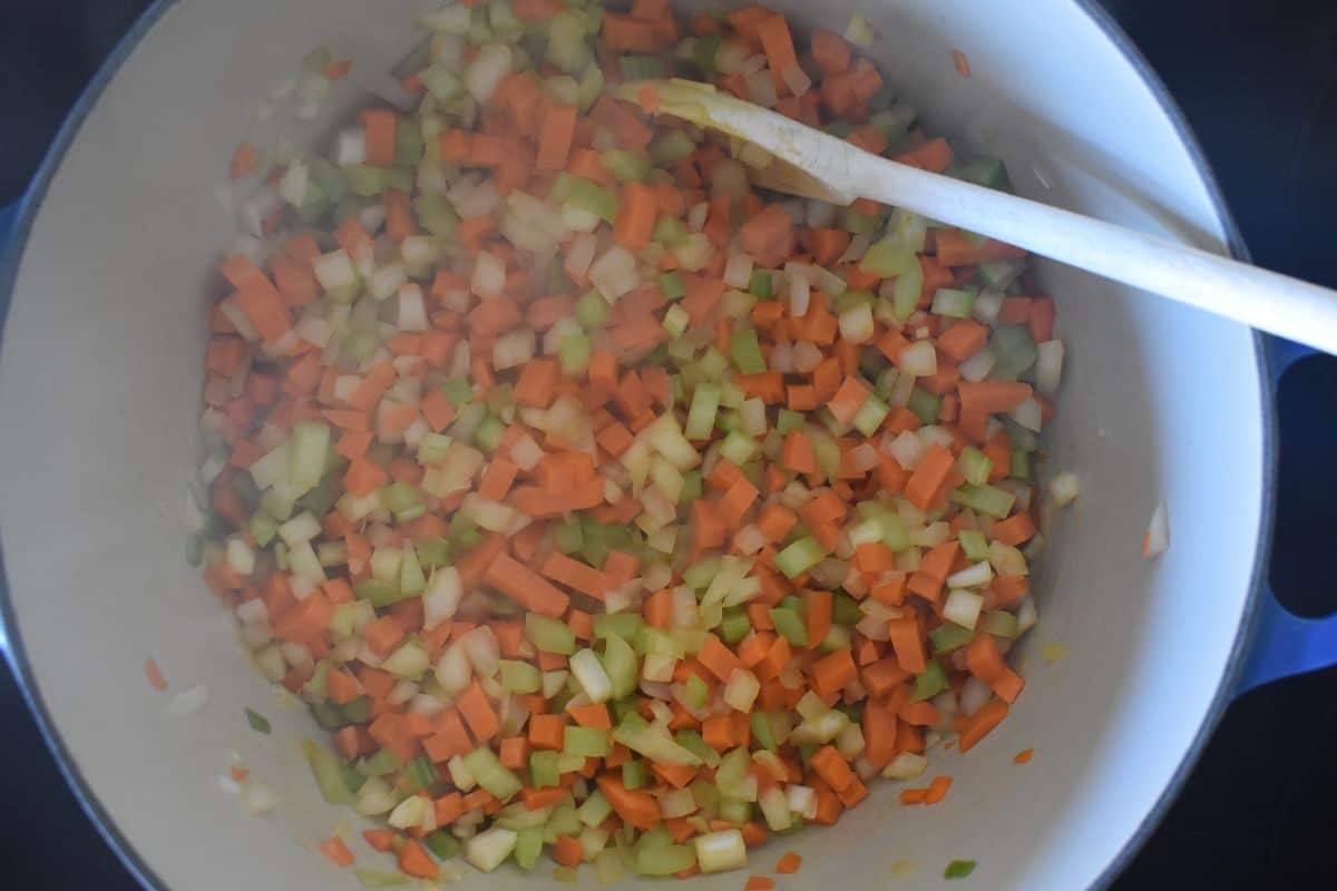 Cooked veggies in a dutch oven with a spoon. 