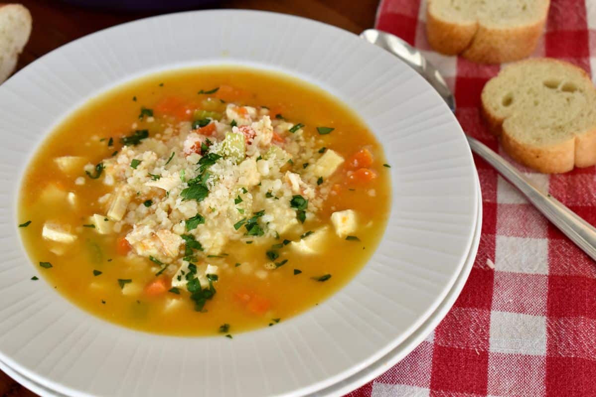 Bowl of Chicken Pastina soup with parmesan cheese and parsley sprinkled on top. 