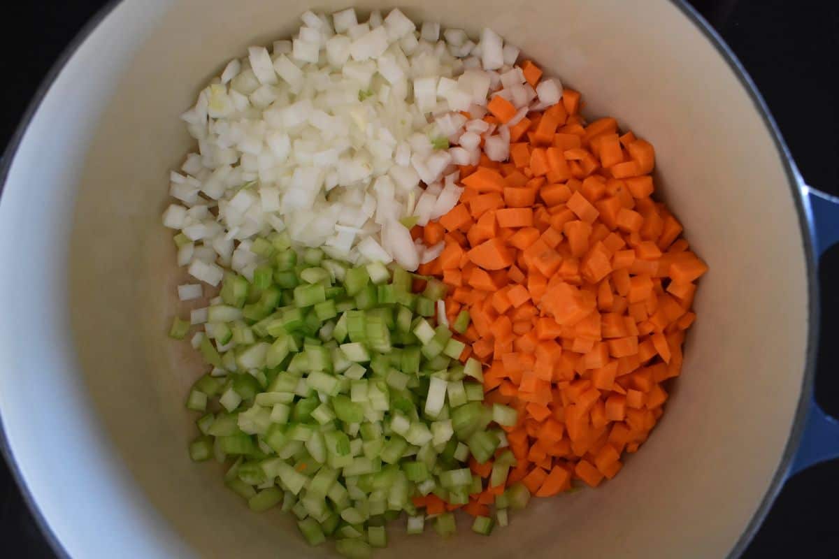 Dutch oven filled with diced onion, carrot, and celery. 