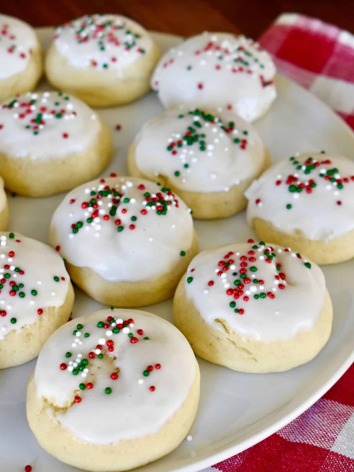 Italian Christmas Cookies on a white plate with a checkered napkin underneath. 