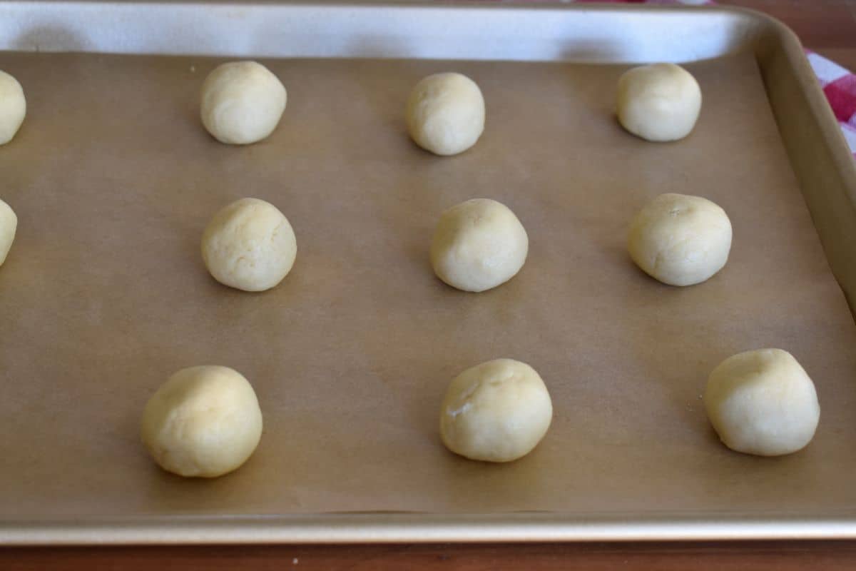 Dough balls on a parchment lined baking sheet. 