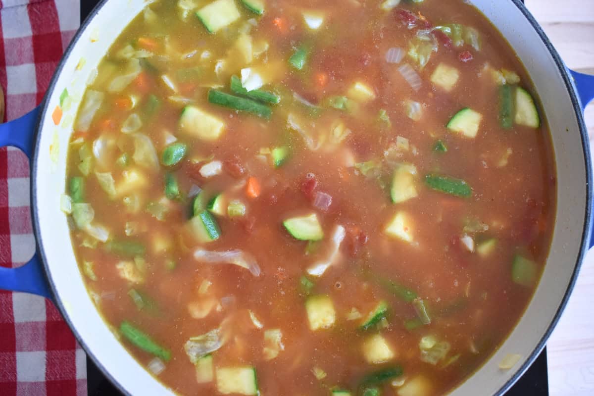 Broth and crushed tomatoes added to the pot. 