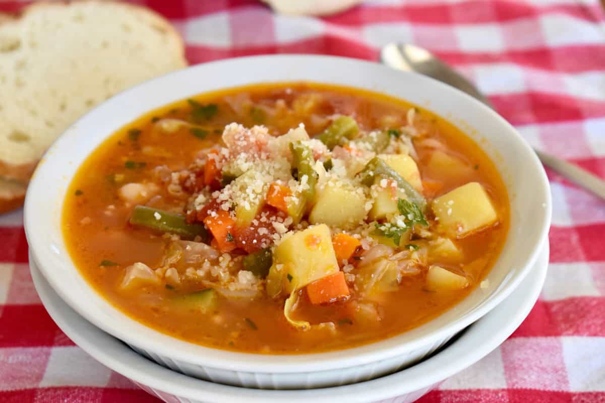 Italian Vegetable Soup in a white bowl with grated parmesan cheese on top. 