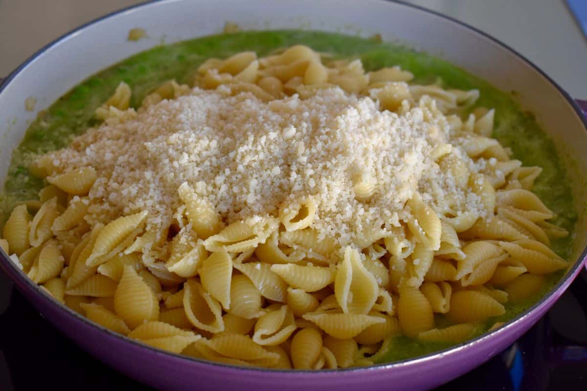 Large dutch oven with pea sauce, cooked shells, and parmesan cheese. 