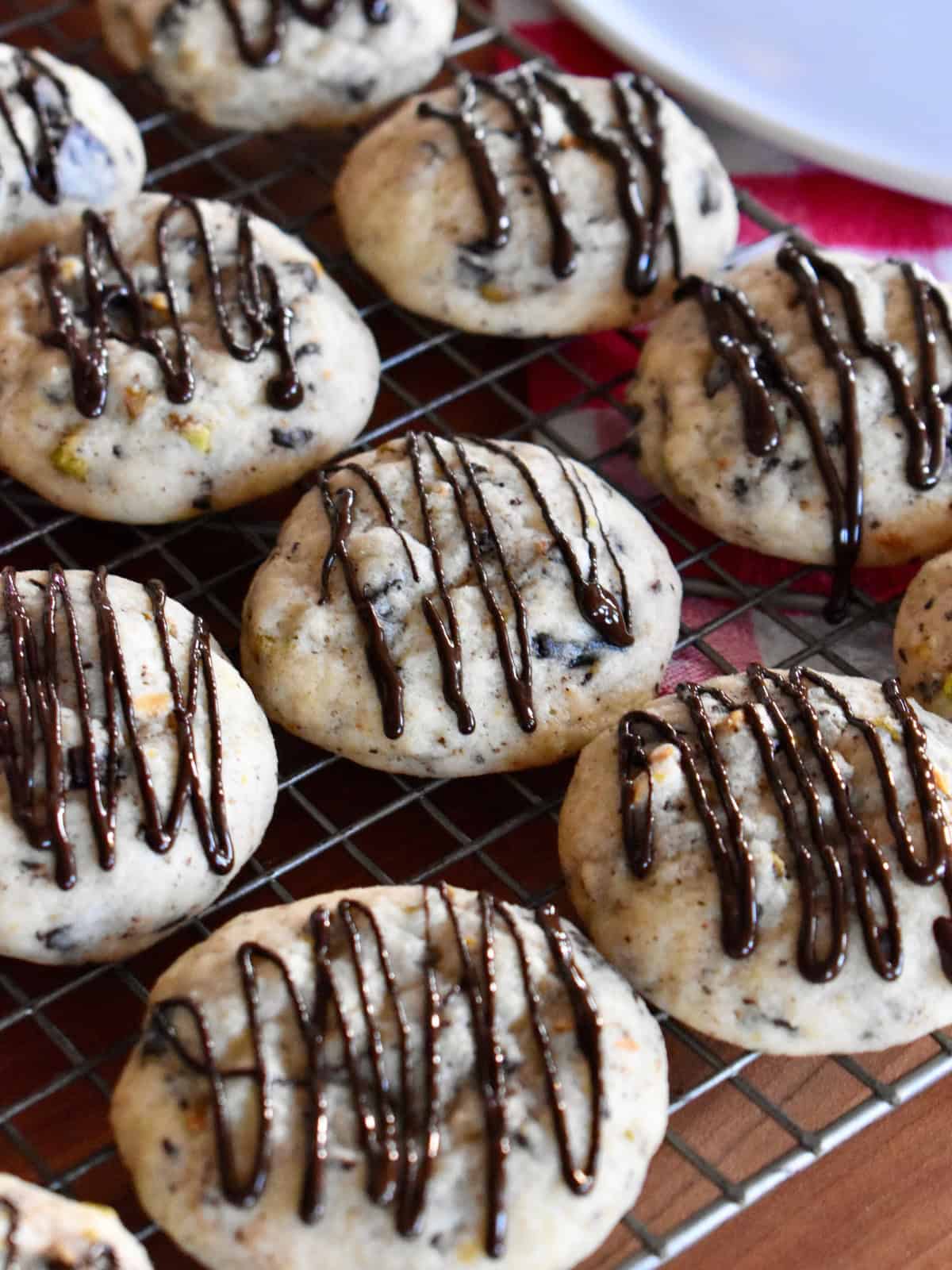 Cannoli Cookies with chocolate drizzle on top on a wire cooling rack. 