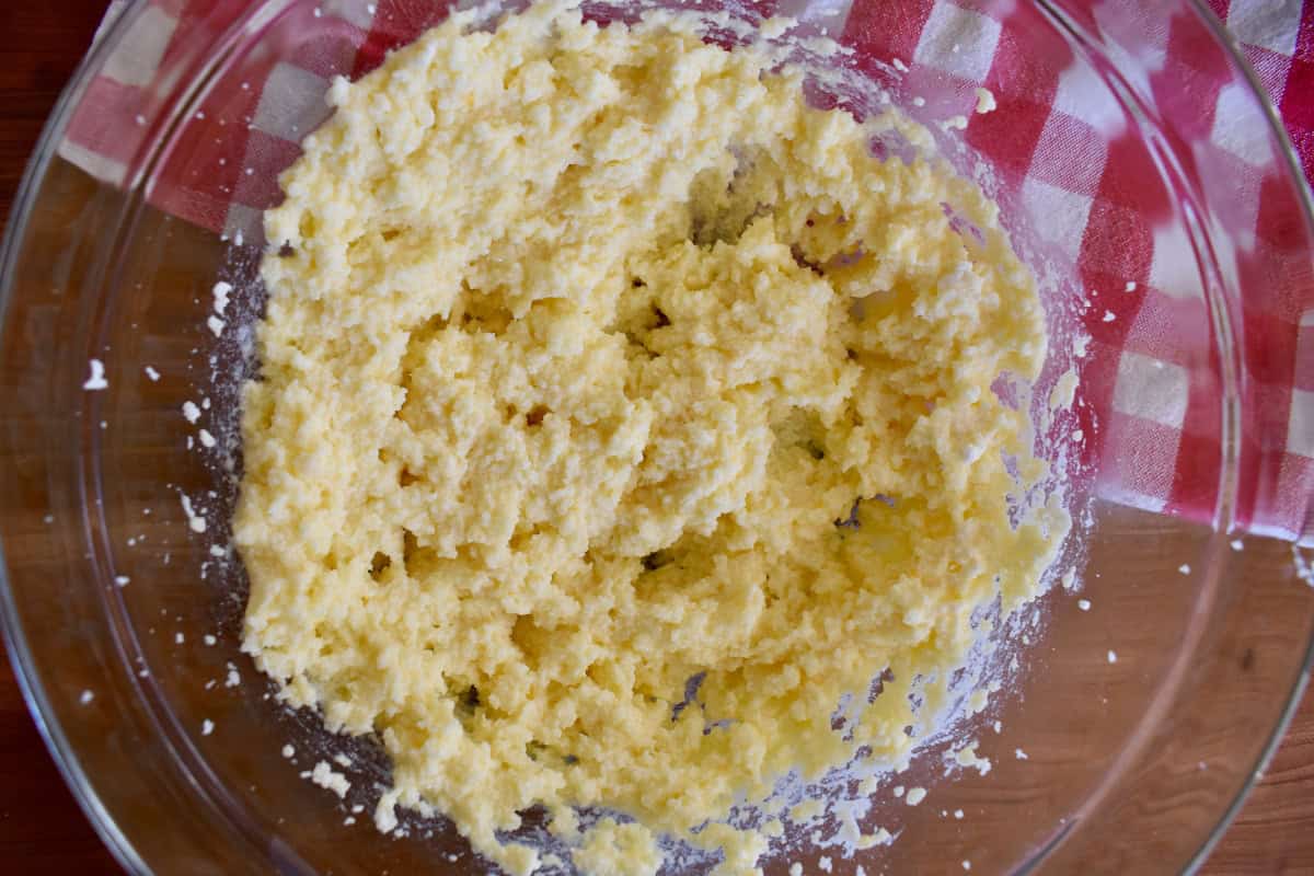 Dough in a glass bowl on a checkered napkin.