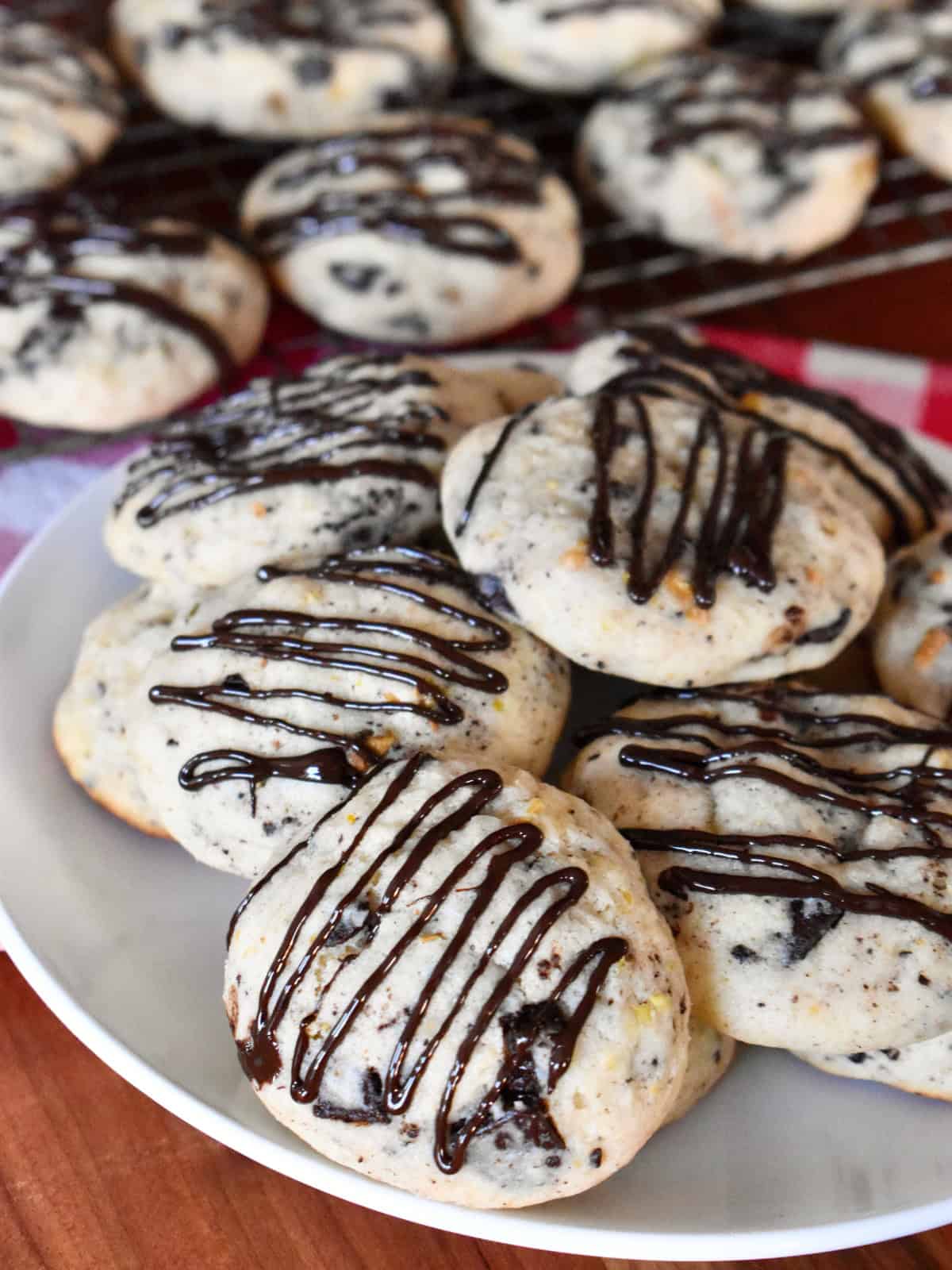 Cannoli Cookies with chocolate drizzle on top on a white plate. 