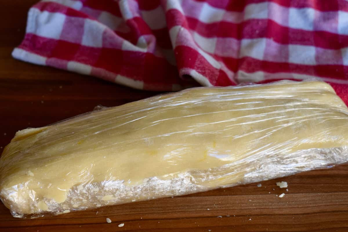 Dough formed into a log shape and wrapped in plastic wrap. 