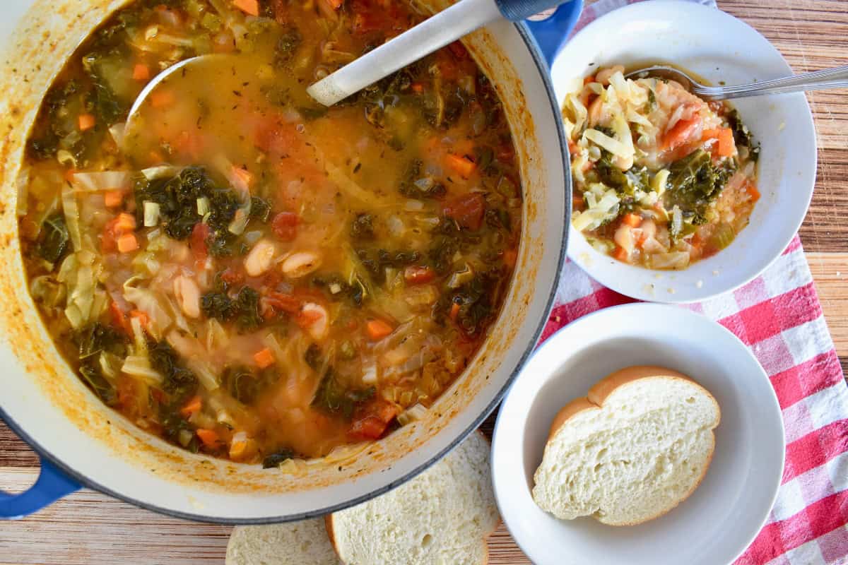 Ribollita soup in a large dutch oven with a bowl of bread next to it.