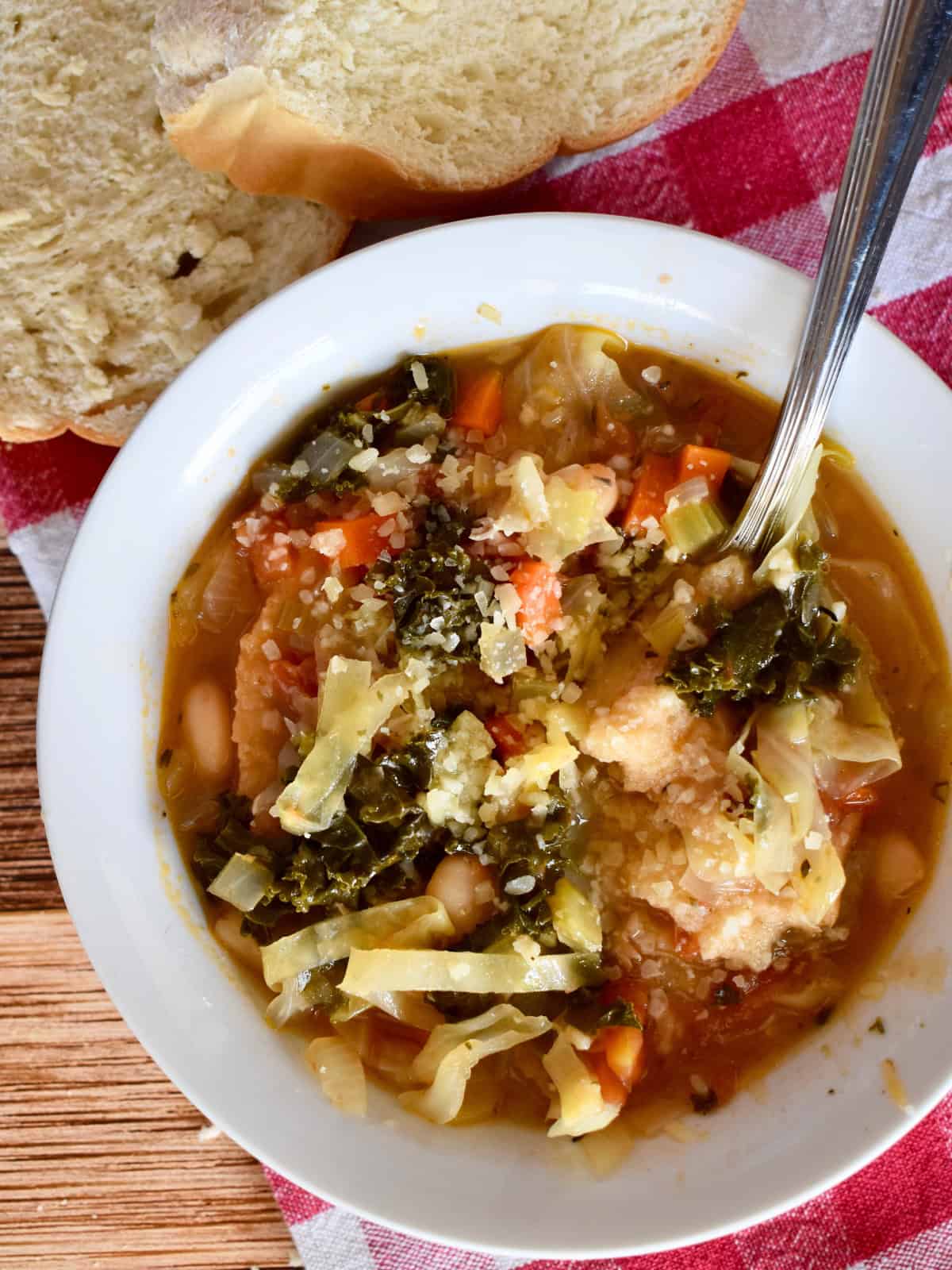 Ribollita soup in a bowl with bread next to it. 