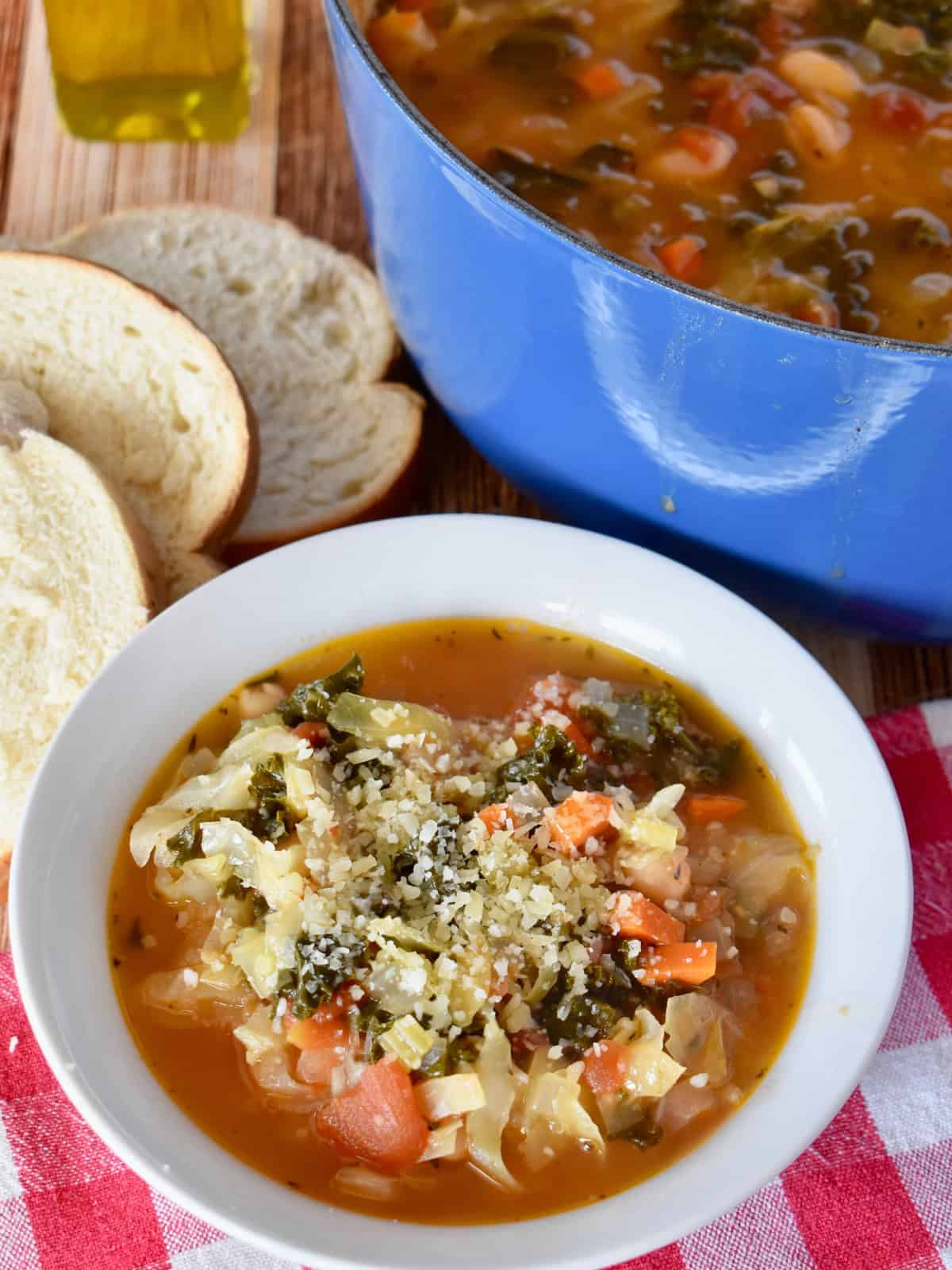 Bowl of Ribollita soup with a spoon in it and sliced bread in the background. 