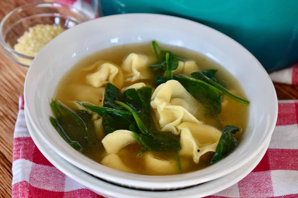 Tortellini en Brodo with spinach in a white bowl. 