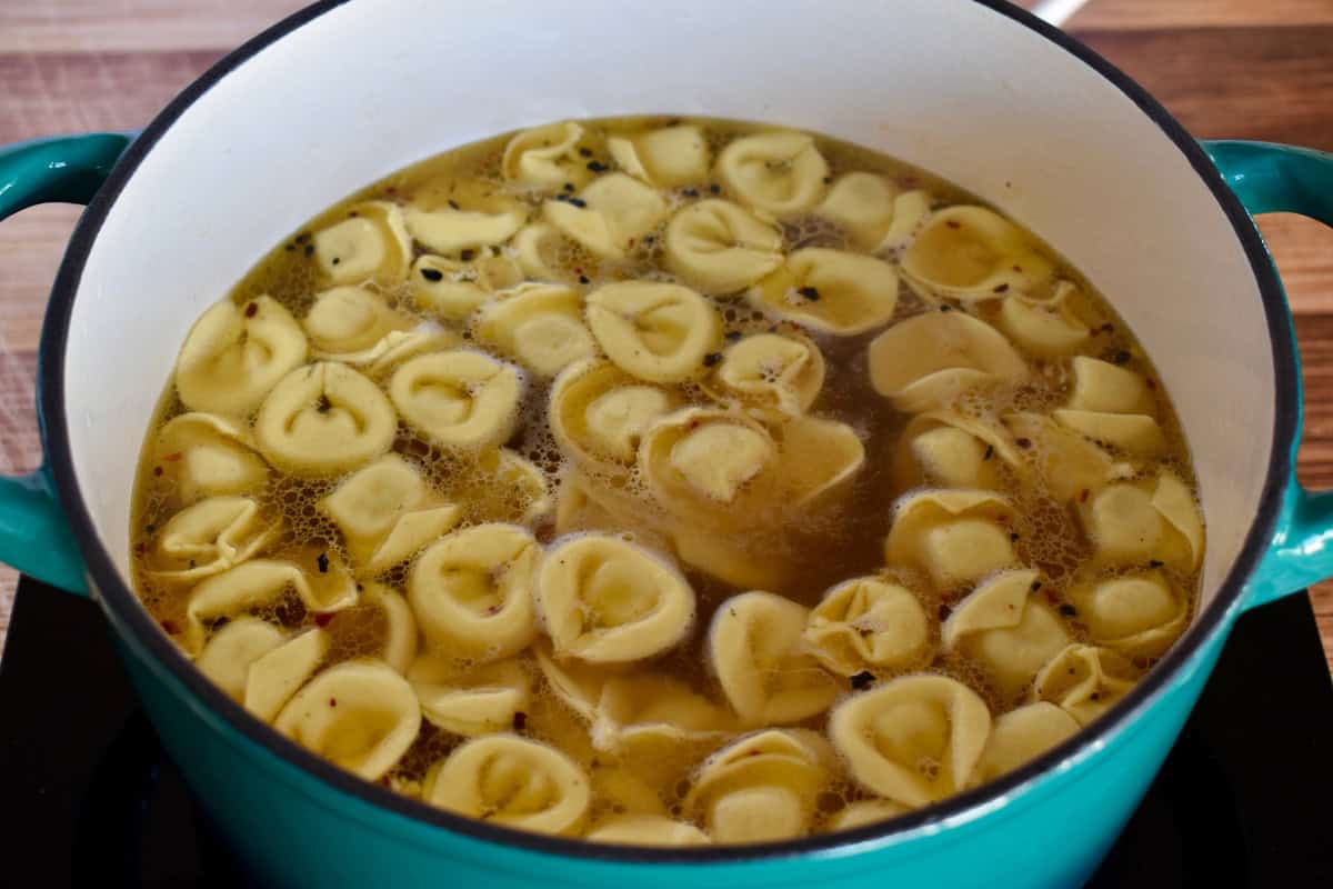 Cheese tortellini added to the broth in the pot. 