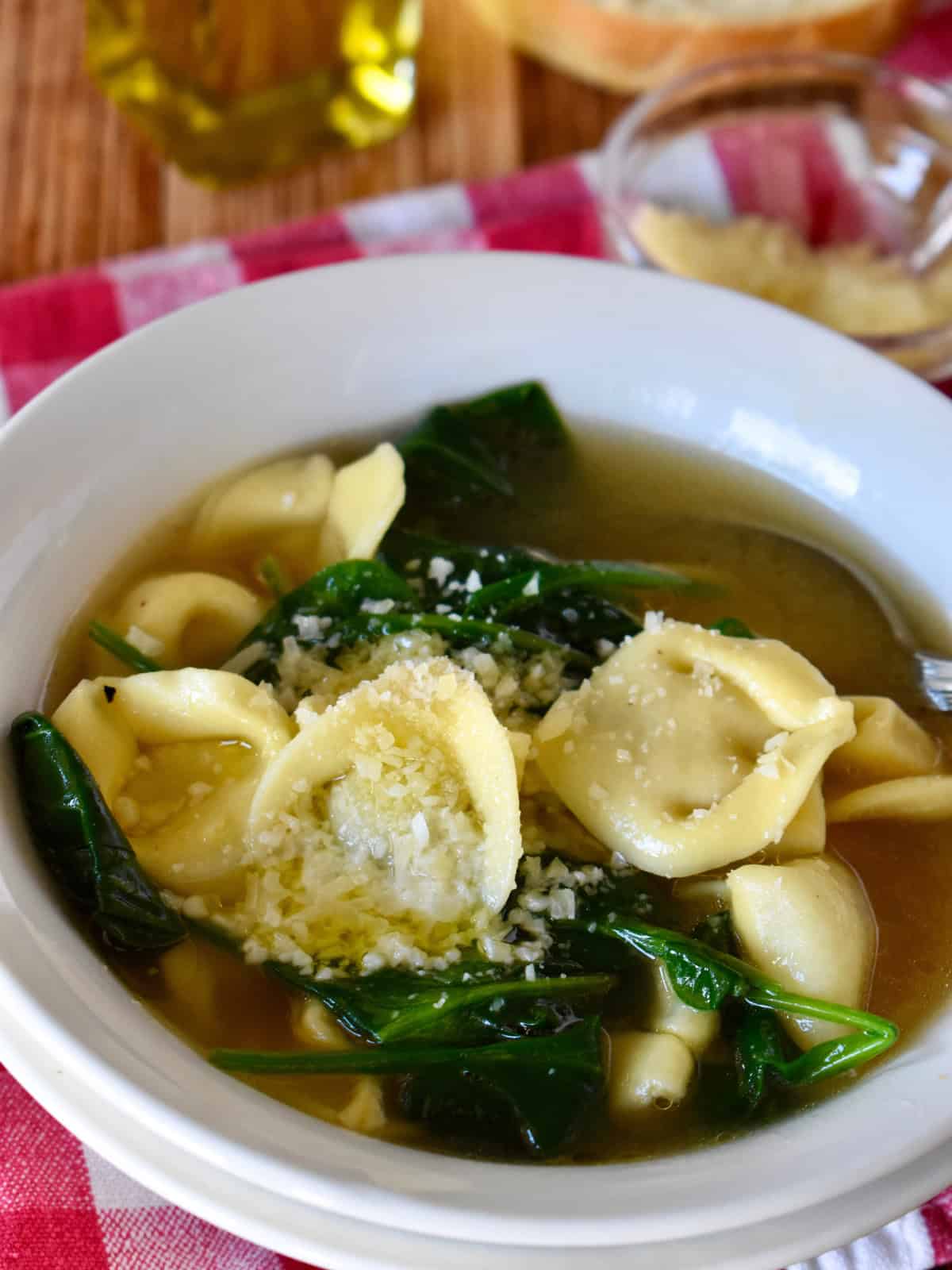 Tortellini en Brodo with spinach in a white bowl. 